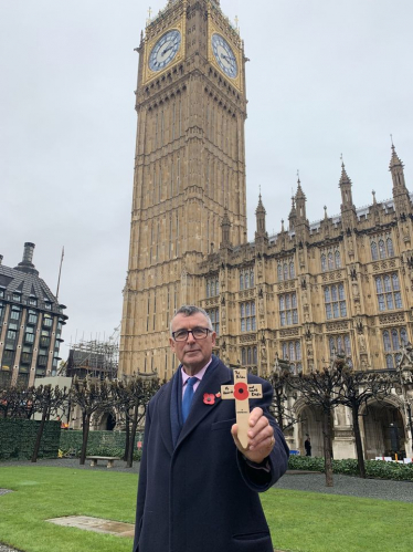 Bernard holding a cross with a poppy on it ready to plant in remembrance 